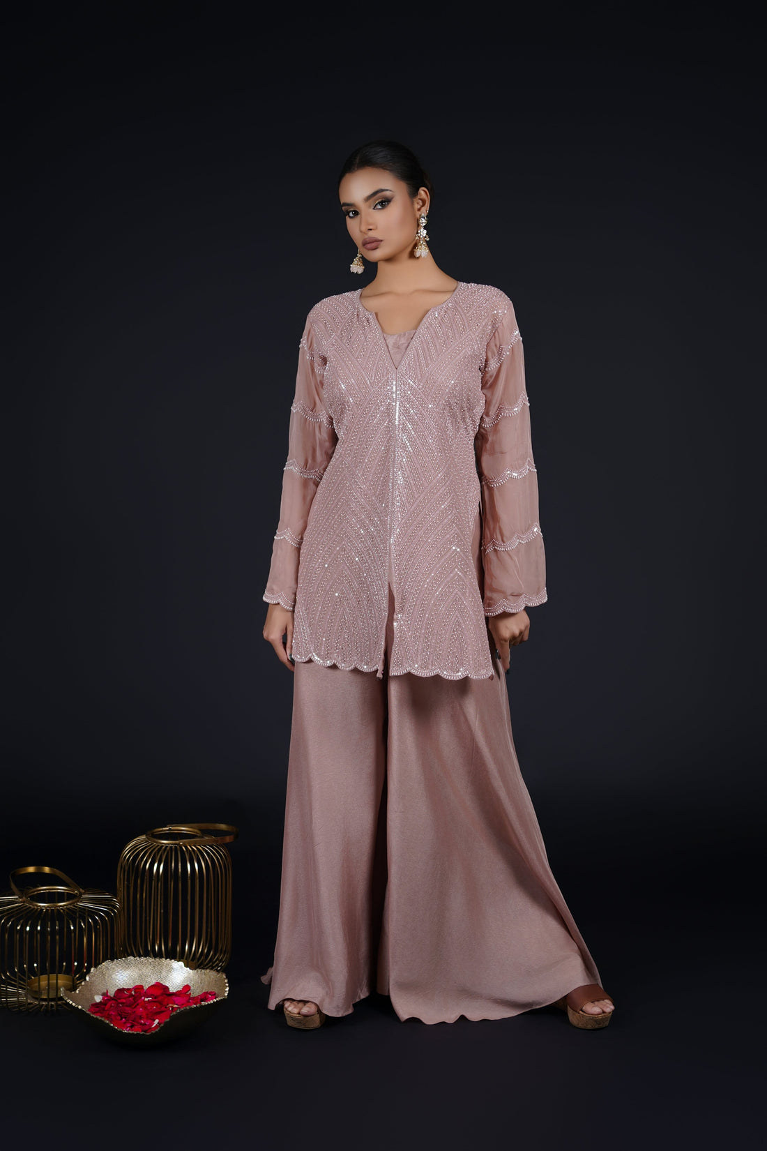 Model wearing an elegant Ash Rose Pink Indowestern outfit consisting of a straight-cut organza kurta embellished with pearls, sequins, and threadwork, paired with umbrella palazzo pants and a coordinating crop top.