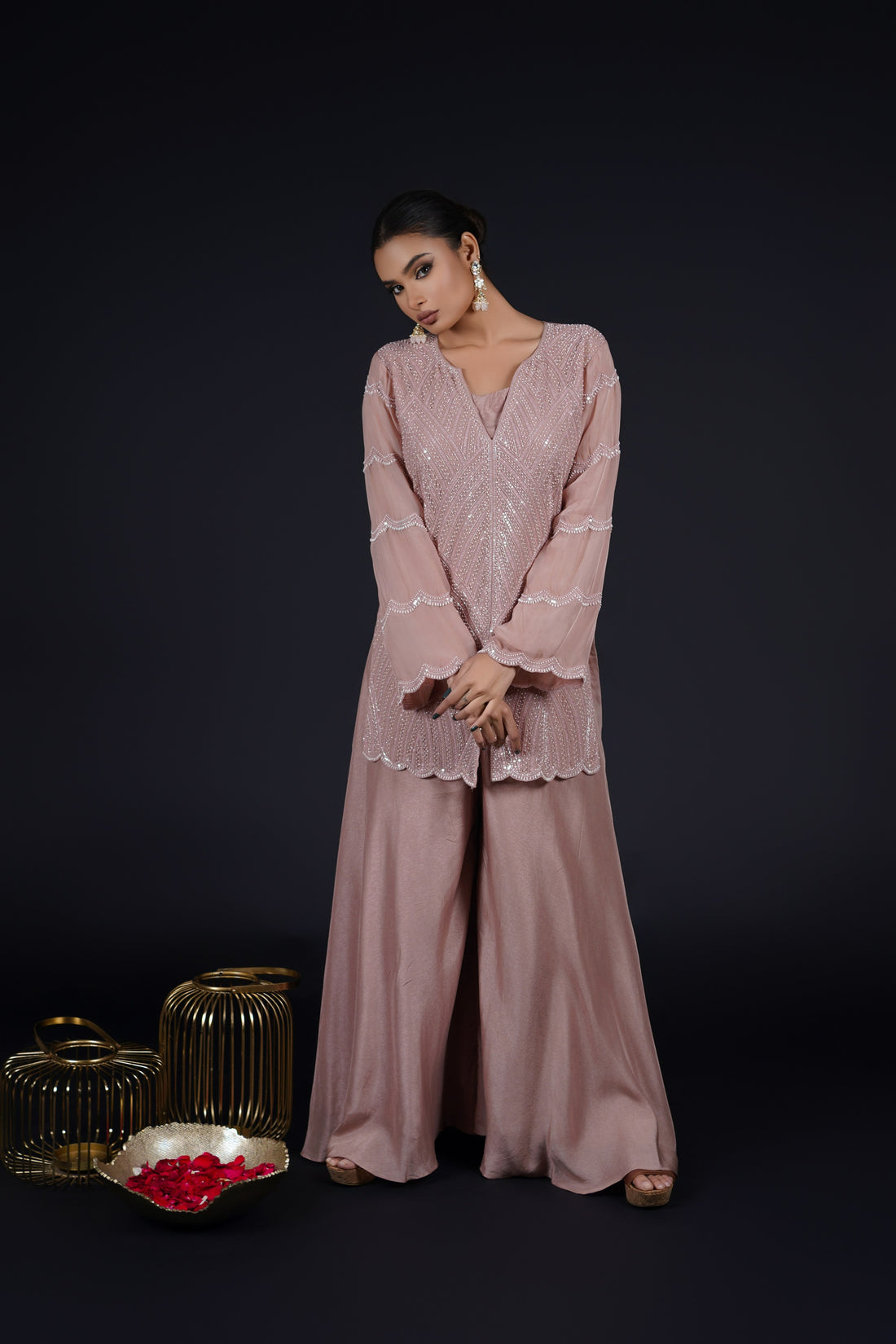 Model wearing an elegant Ash Rose Pink Indowestern outfit consisting of a straight-cut organza kurta embellished with pearls, sequins, and threadwork, paired with umbrella palazzo pants and a coordinating crop top.