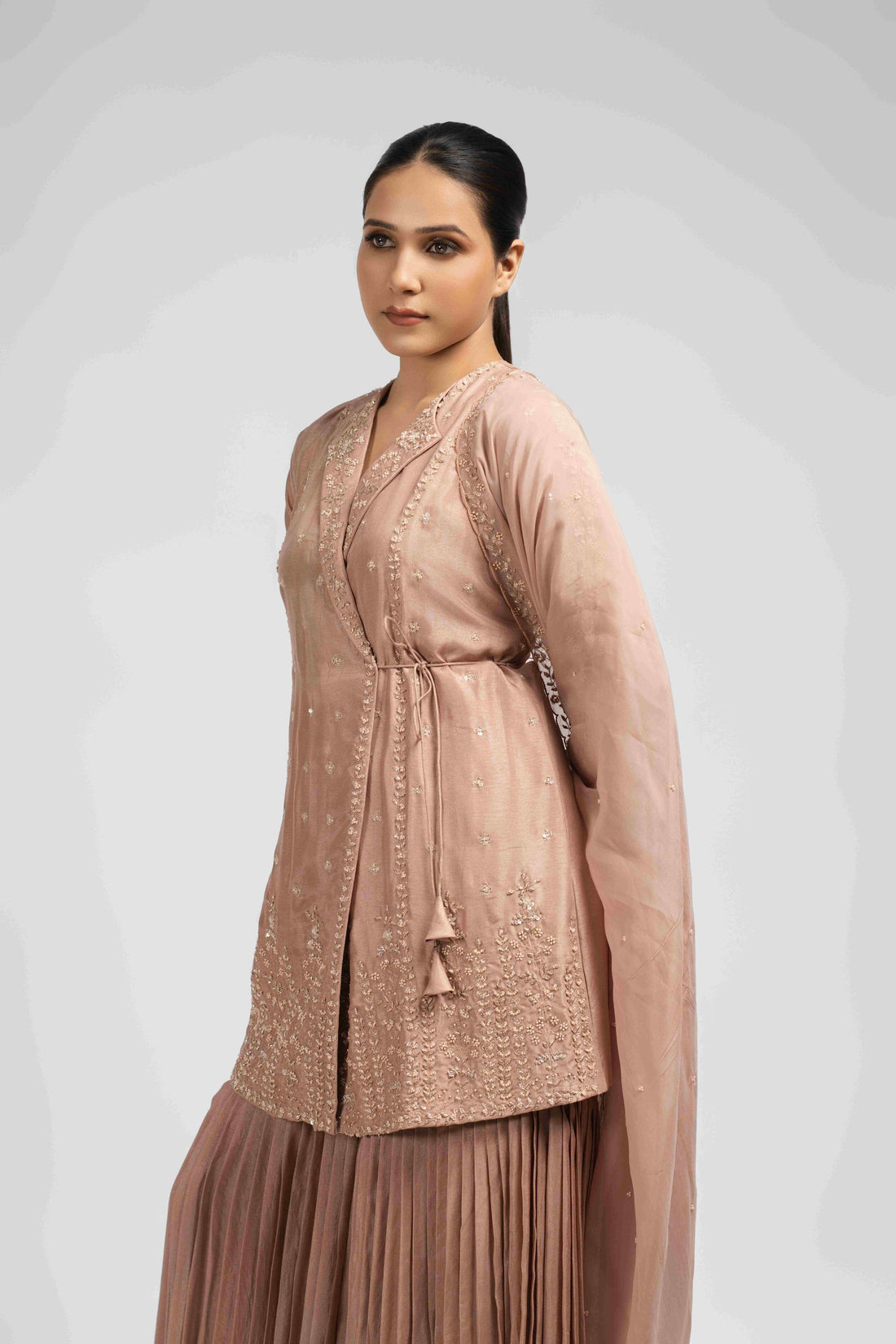 Ash rose pink sharara suit featuring an angrakha-style kurta with lapel collar, intricate zardozi, kasab, pearl, and sequin work, paired with pleated sharara pants and an organza dupatta for a timeless festive look.