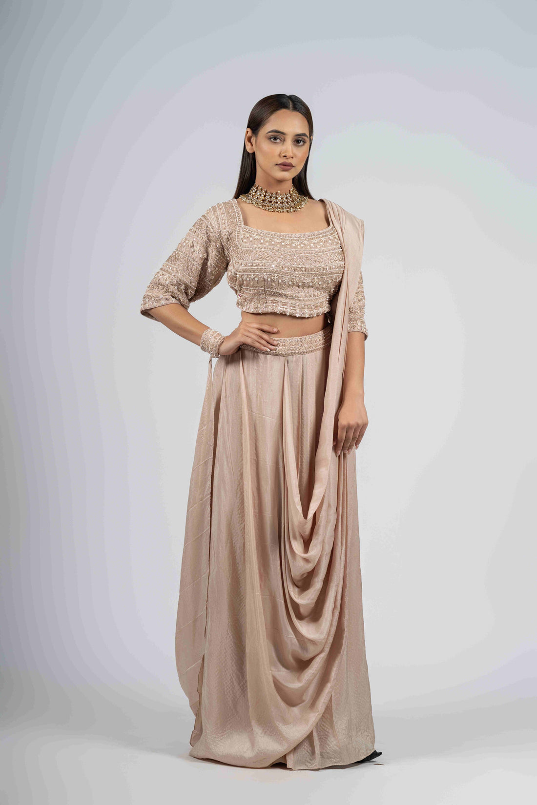 Ivory silk drape style Indo-Western set with an embellished blouse featuring pearl, kasab, zardozi, and sequin work, elbow-length sleeves, and a front cowl design. Perfect for weddings and festive occasions.