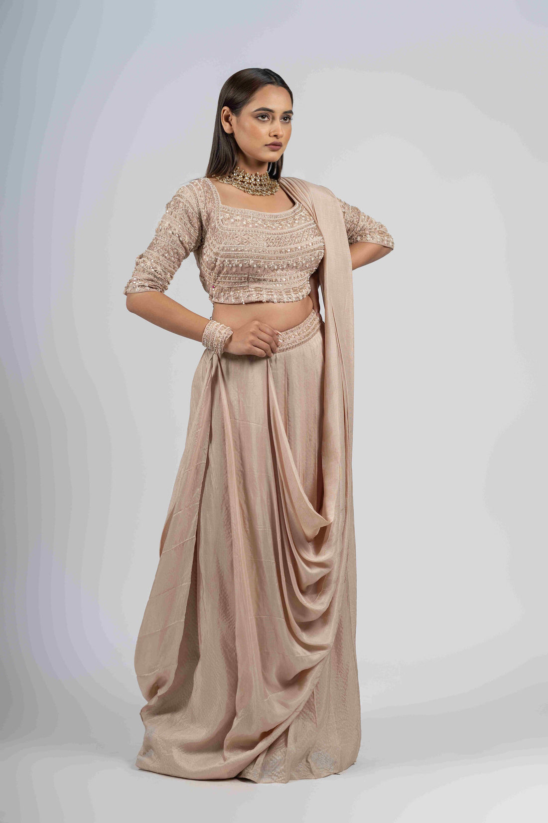 Ivory silk drape style Indo-Western set with an embellished blouse featuring pearl, kasab, zardozi, and sequin work, elbow-length sleeves, and a front cowl design. Perfect for weddings and festive occasions.