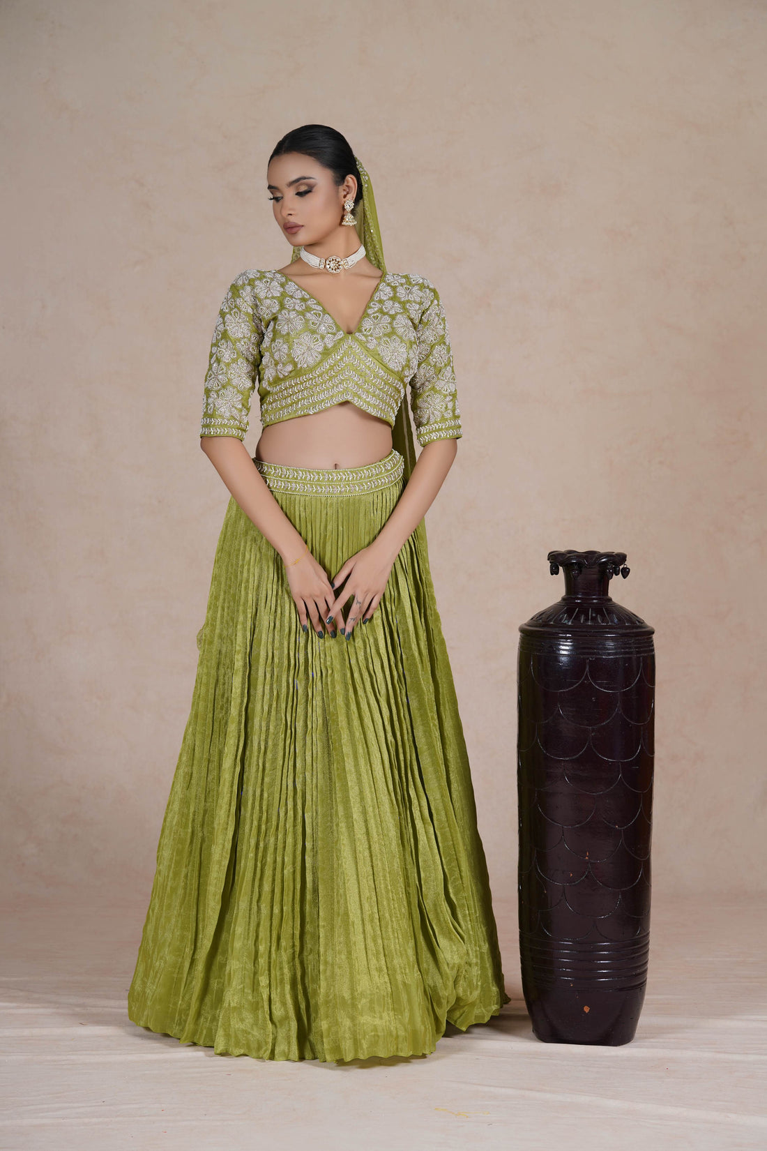 A lime green embroidered lehenga set featuring a pleated skirt, intricately designed blouse with 3/4th sleeves, and a matching dupatta with pearl and bead detailing. Perfect for weddings and festive occasions.