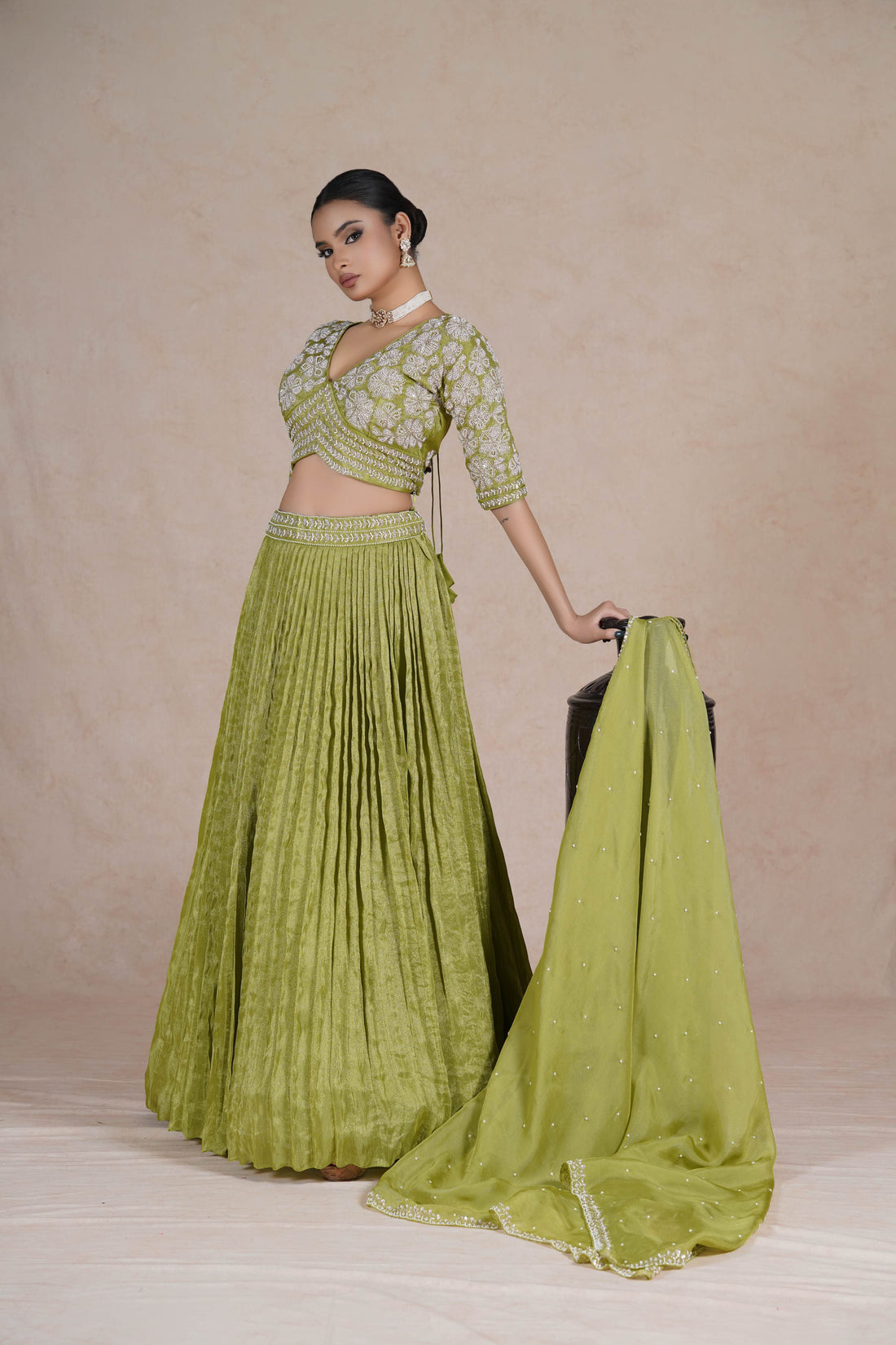 A lime green embroidered lehenga set featuring a pleated skirt, intricately designed blouse with 3/4th sleeves, and a matching dupatta with pearl and bead detailing. Perfect for weddings and festive occasions.
