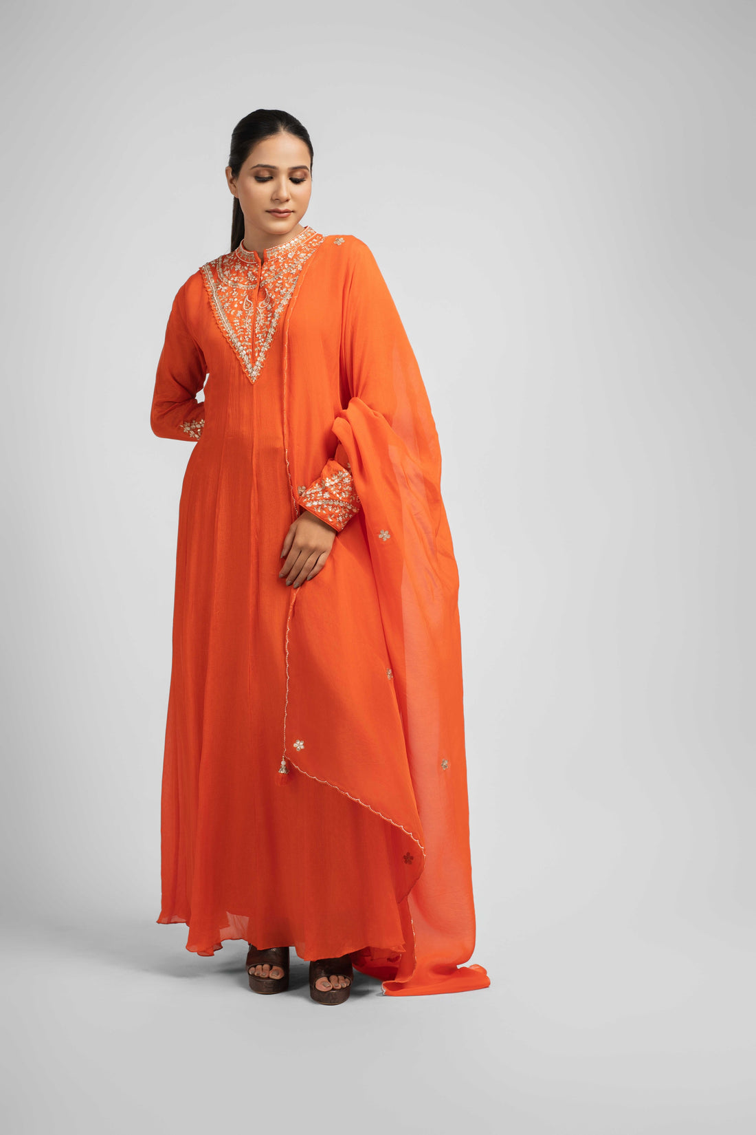 Orange chinnon kali anarkali suit with intricate embellishments on the neck and cuffs, paired with an organza dupatta featuring kasab, pearl, and gotta patti work – perfect for festive and wedding wear.