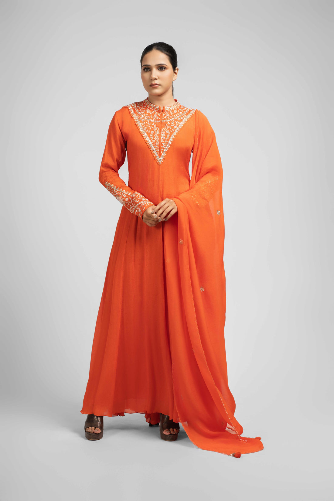 Orange chinnon kali anarkali suit with intricate embellishments on the neck and cuffs, paired with an organza dupatta featuring kasab, pearl, and gotta patti work – perfect for festive and wedding wear.
