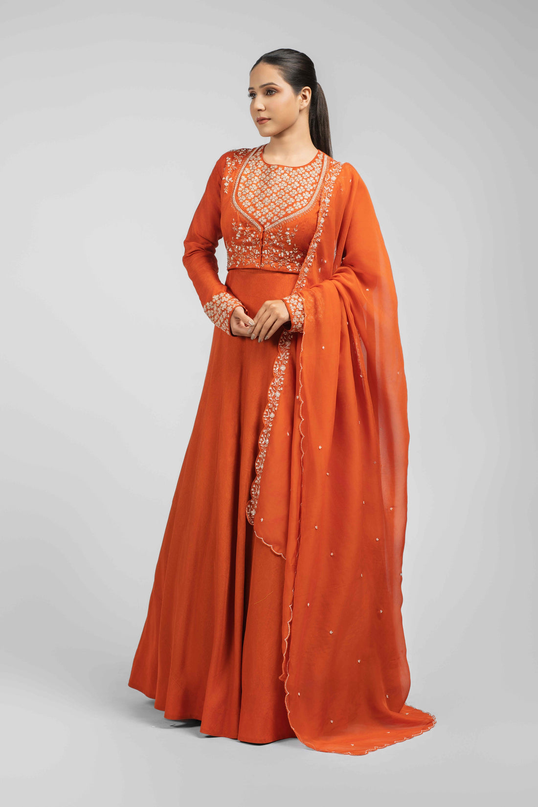 Orange silk double-layer gown with embellished bodice and cuffs, paired with an organza dupatta featuring kasab, zardozi, sequins, and pitai work – perfect for festive and wedding wear.