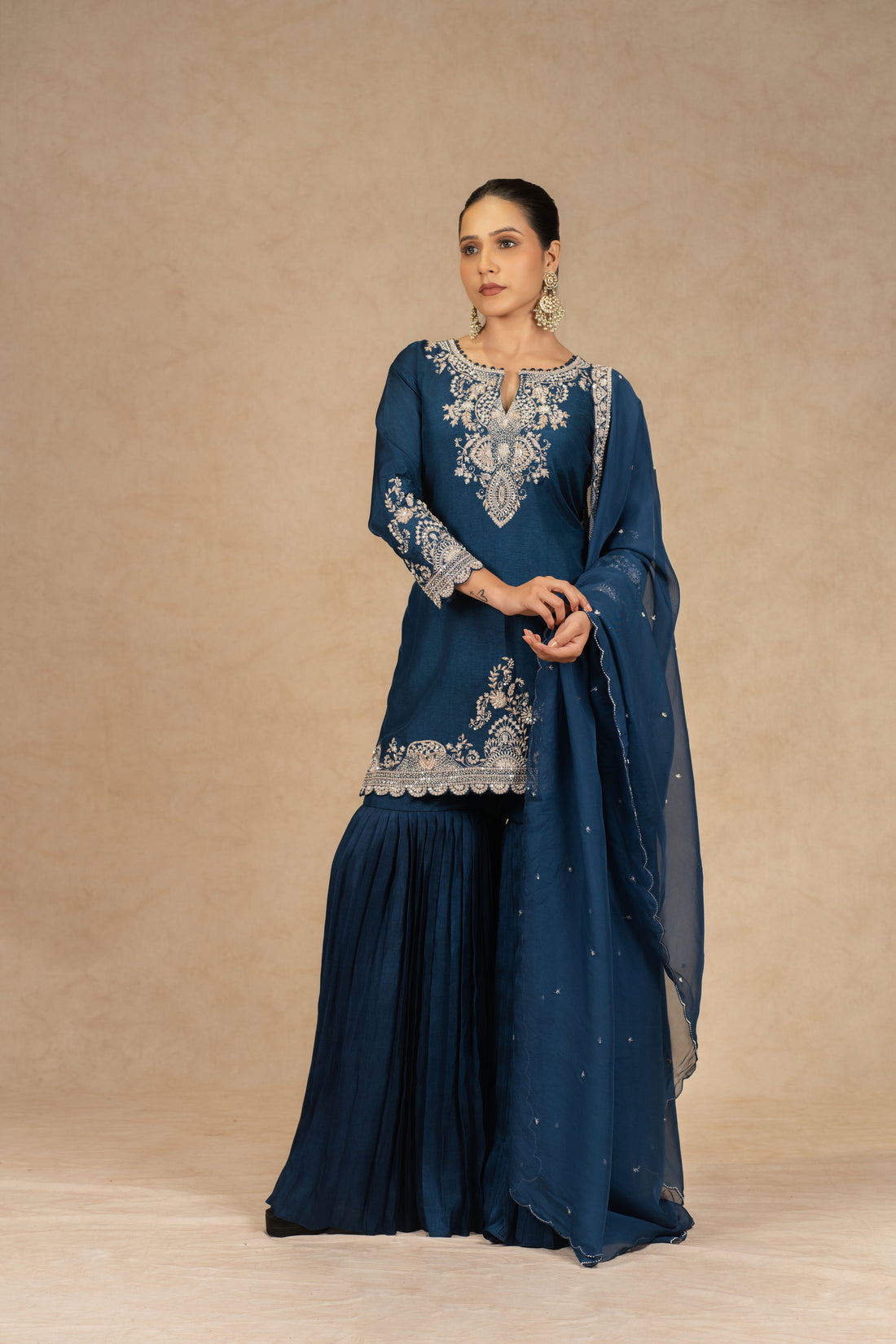 Peacock blue embroidered sharara suit with silk kurta, pleated sharara, and organza dupatta featuring intricate dabka, kasab, sequins, and pearl embellishments – perfect for festive and wedding occasions.