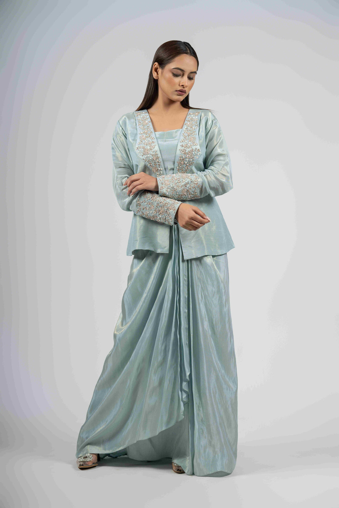 Powder blue indo-western set featuring an embellished lapel collar blazer, sleeveless blouse, and dhoti pleated skirt with intricate pearl, kasab, sequin, and zardozi embellishments. Ideal for festive and formal occasions.