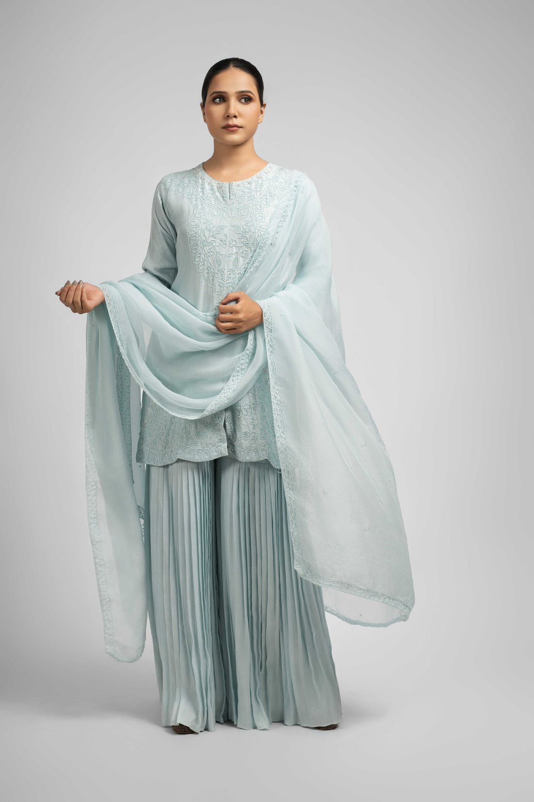 Powder blue silk sharara set with pleated pants and an embellished organza dupatta, featuring intricate pearl, sequin, and thread work detailing for a sophisticated ethnic look.