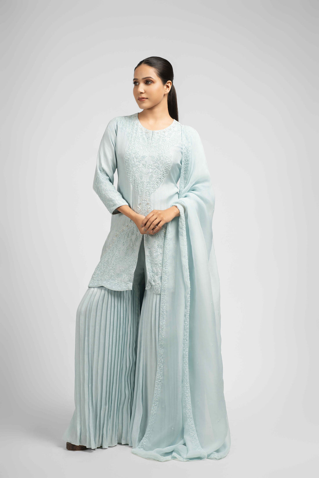 Powder blue silk sharara set with pleated pants and an embellished organza dupatta, featuring intricate pearl, sequin, and thread work detailing for a sophisticated ethnic look.