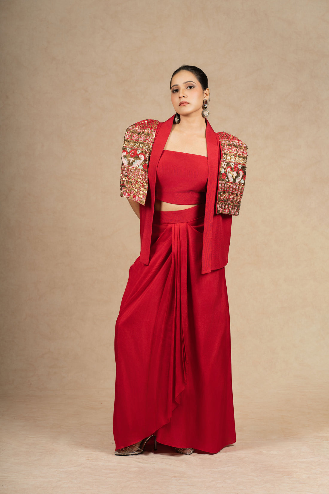 Red silk Indowestern outfit featuring a bustier and drape skirt, adorned with antique sequin, pearl embellishments, and intricate thread embroidery.