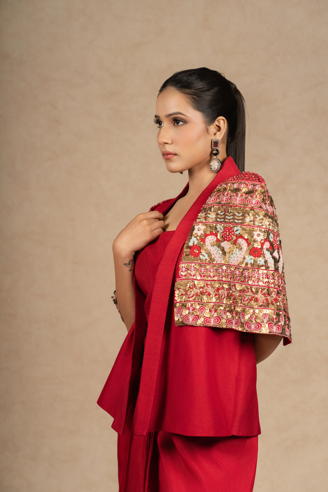 Red silk Indowestern outfit featuring a bustier and drape skirt, adorned with antique sequin, pearl embellishments, and intricate thread embroidery.