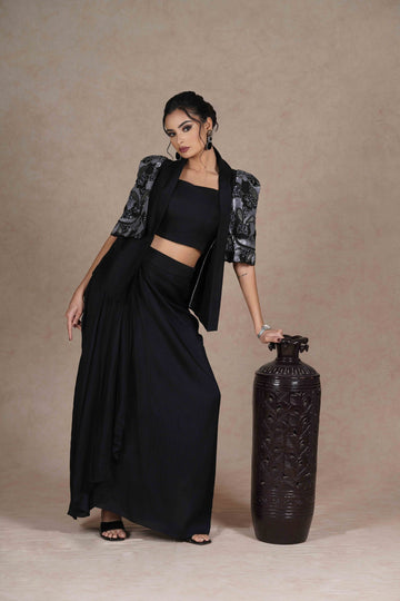 Black and gray embroidered jacket with cape sleeves, sweetheart neckline bustier, and pre-draped silk skirt. Elegant and lightweight festive wear.