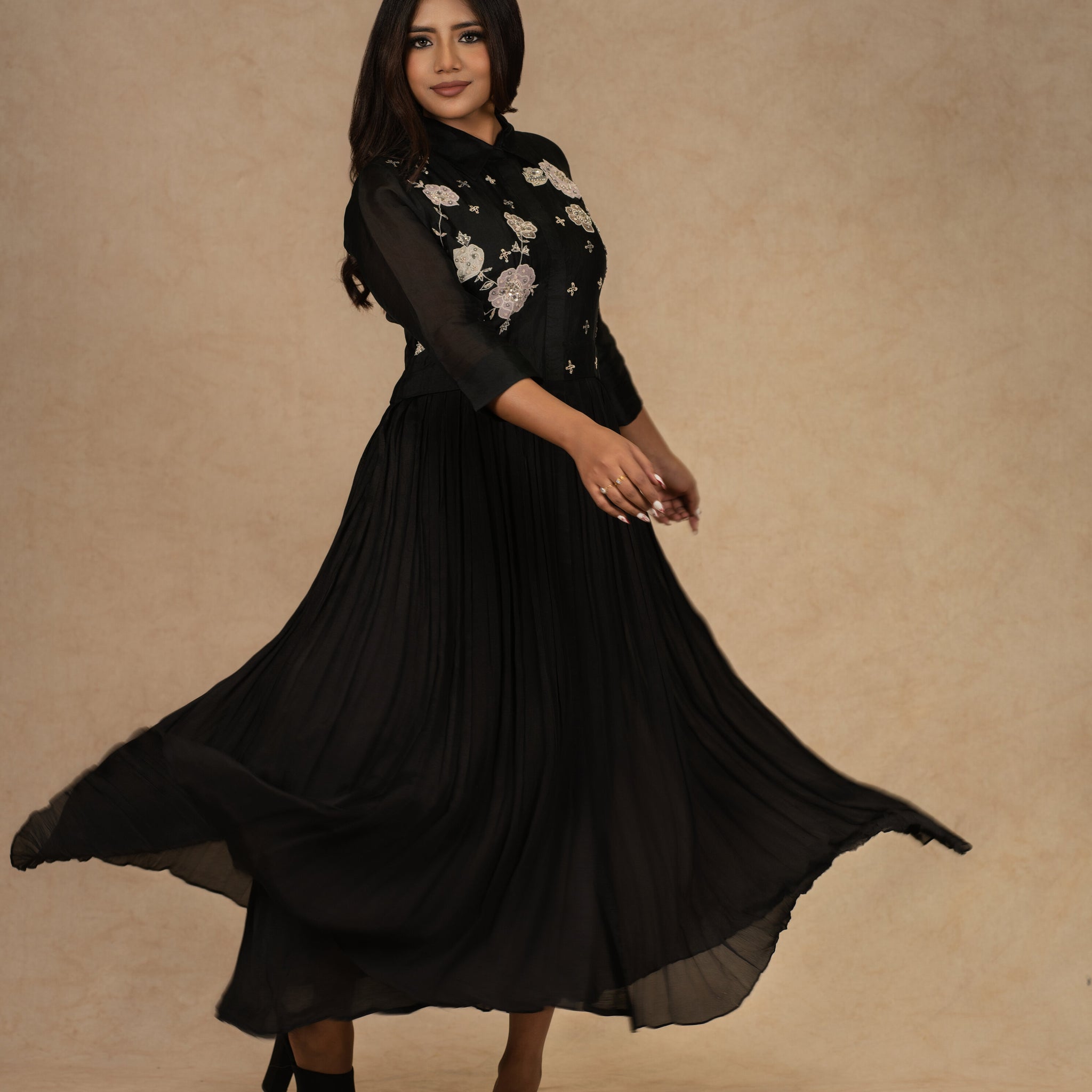 A black organza pleated shirt dress featuring applique floral designs and intricate zardozi work, ideal for festive and formal occasions.