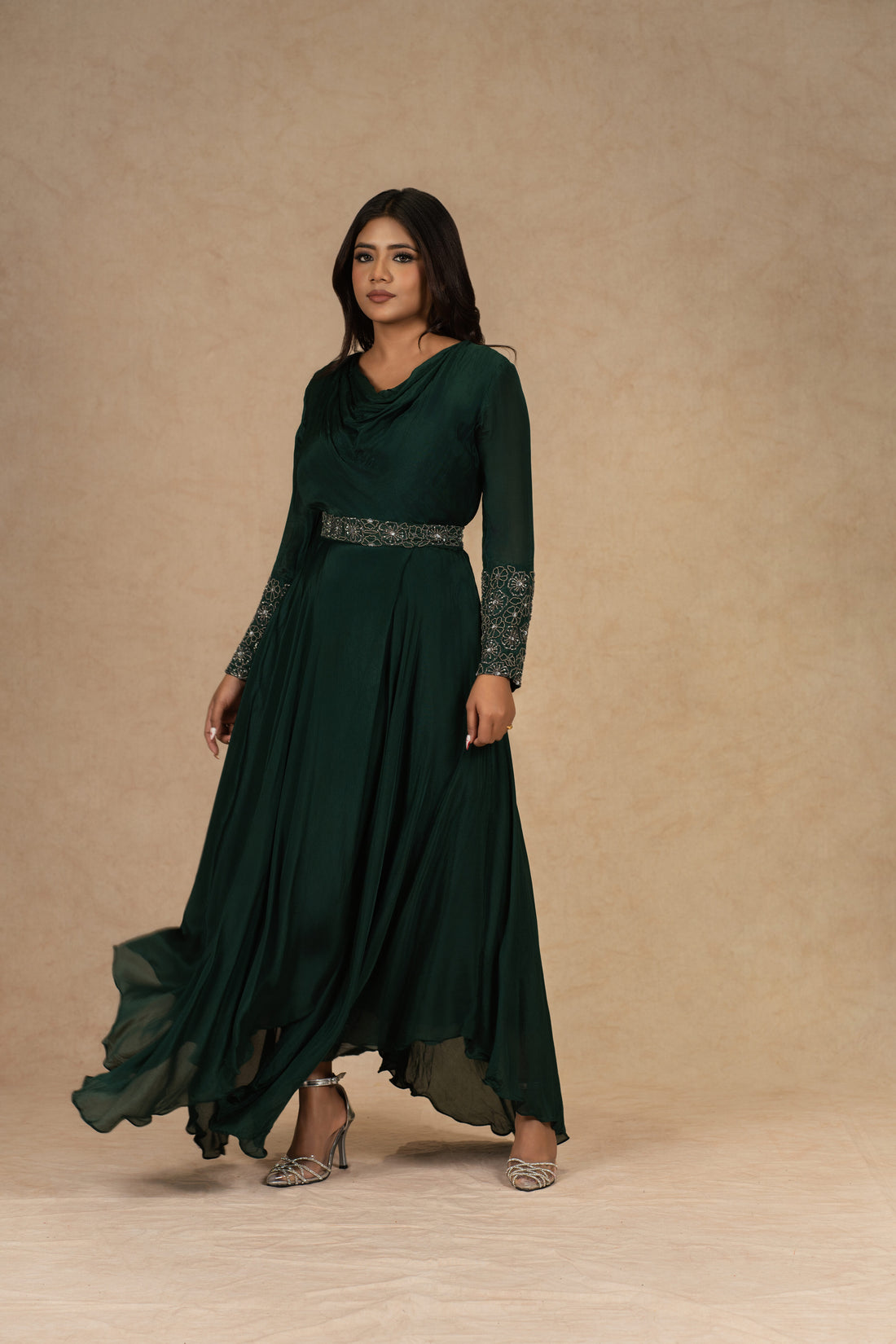 A model wearing a Bottle Green Chinnon Gown with an Ivory Organza Indowestern drape skirt and a bustier, adorned with dori work and pearl embellishments, styled for festive or formal occasions.