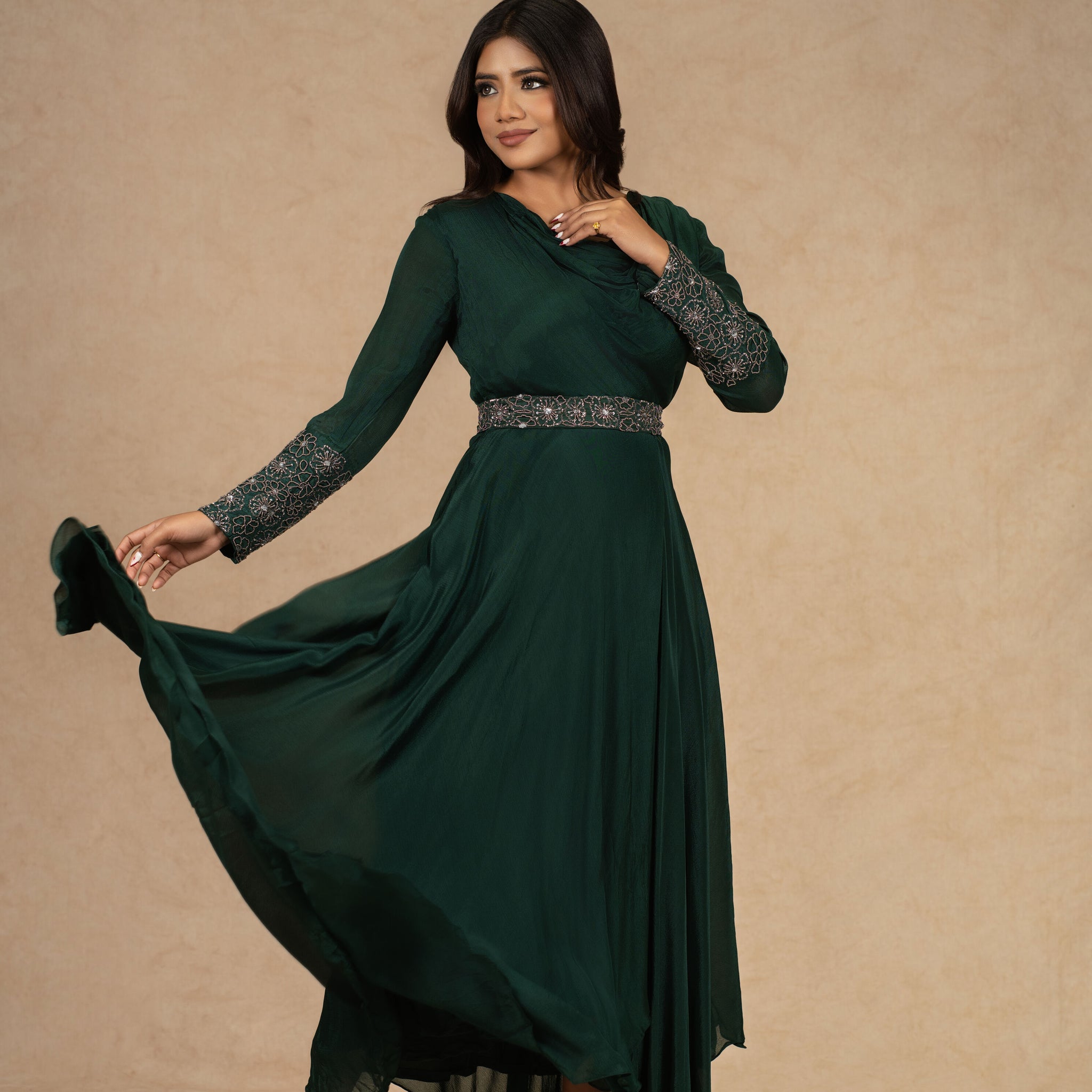 A model wearing a Bottle Green Chinnon Gown with an Ivory Organza Indowestern drape skirt and a bustier, adorned with dori work and pearl embellishments, styled for festive or formal occasions.