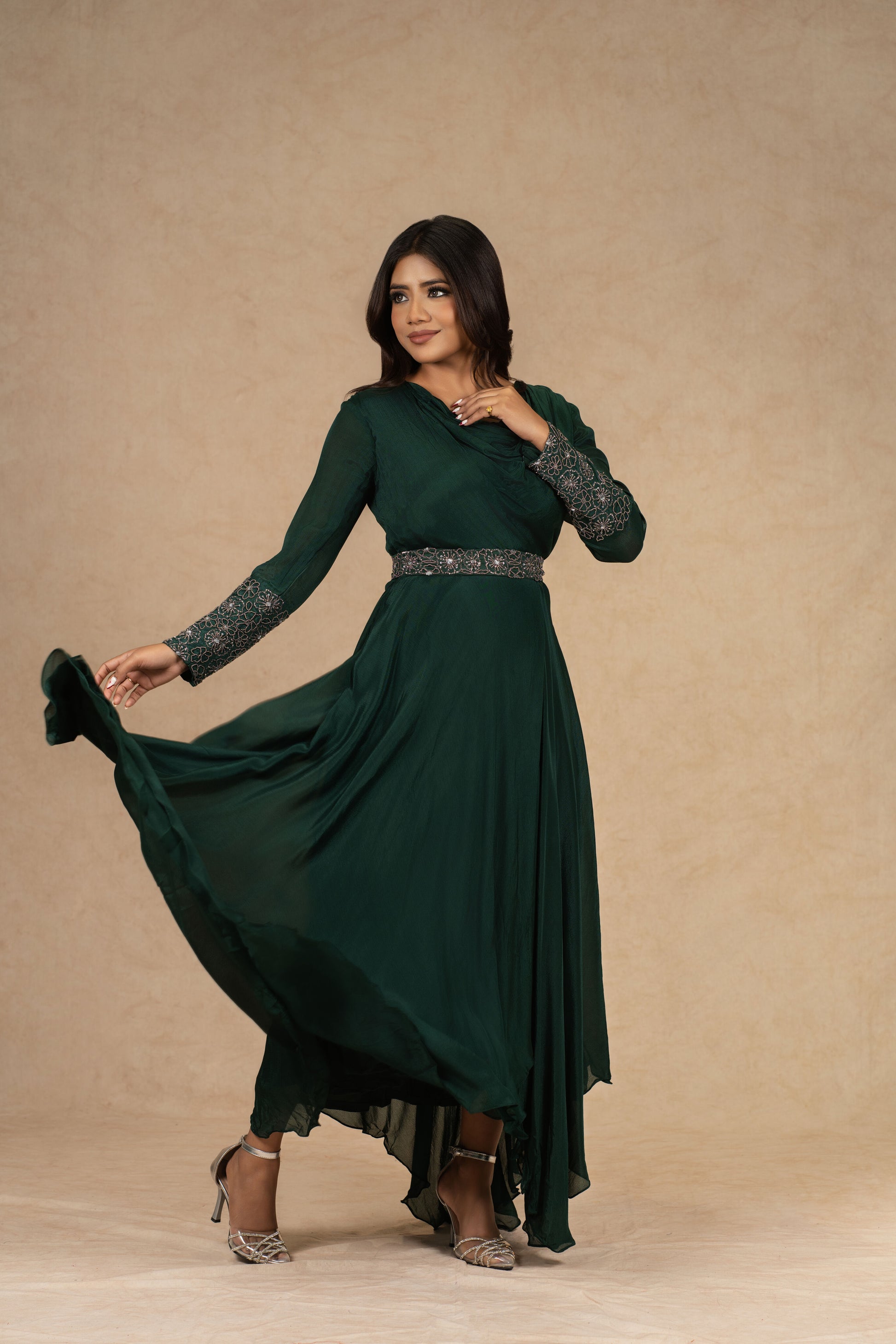 A model wearing a Bottle Green Chinnon Gown with an Ivory Organza Indowestern drape skirt and a bustier, adorned with dori work and pearl embellishments, styled for festive or formal occasions.