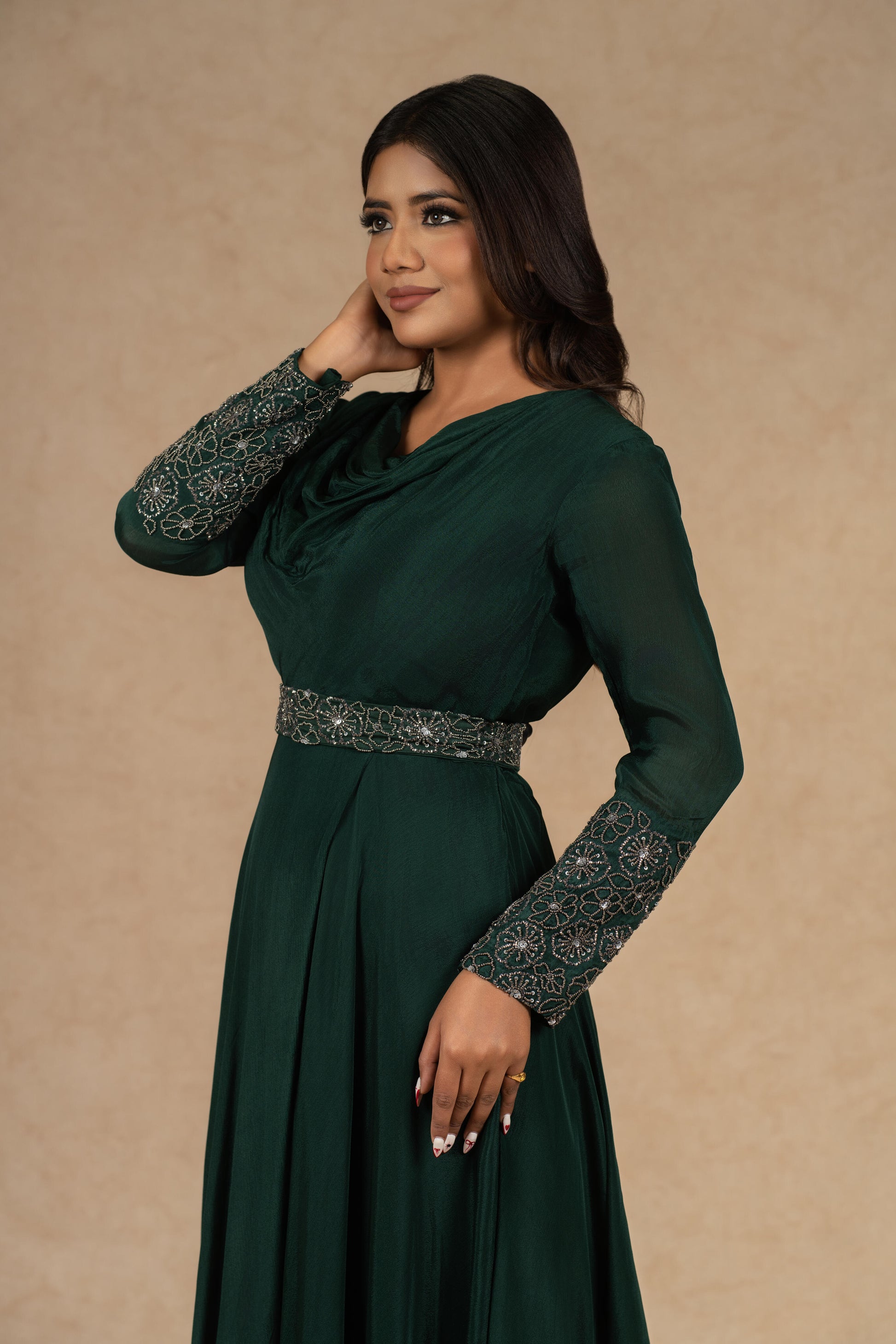 A model wearing a Bottle Green Chinnon Gown with an Ivory Organza Indowestern drape skirt and a bustier, adorned with dori work and pearl embellishments, styled for festive or formal occasions.