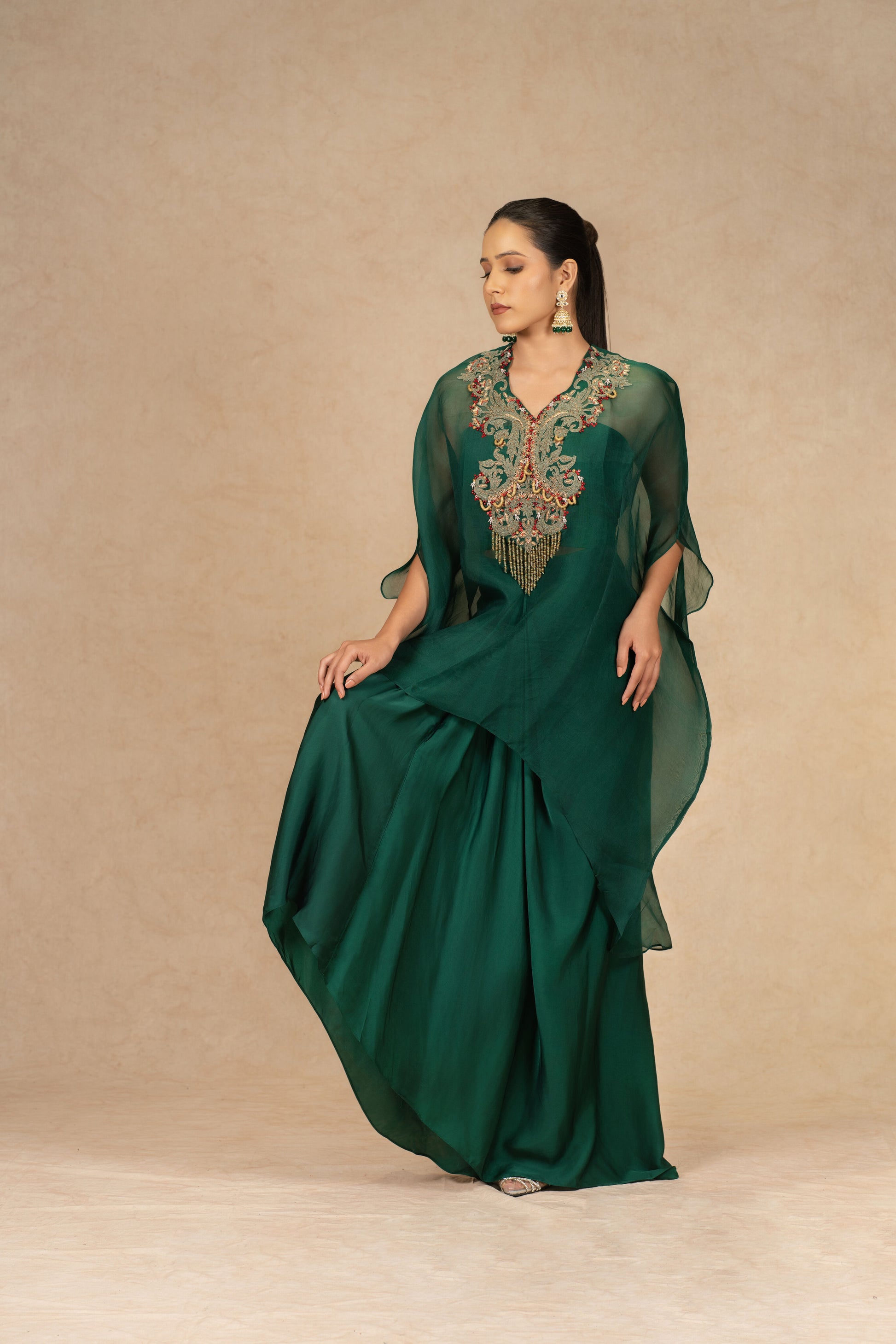 Full-length view of a model styling the Bottle Green Organza Indowestern outfit, featuring a structured drape skirt and cape overlay.