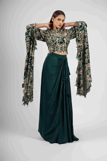 Green crepe crop top with cape sleeves and matching drape skirt embellished with kasab, sequins, thread, and cutdana embroidery – Indo-western festive outfit.