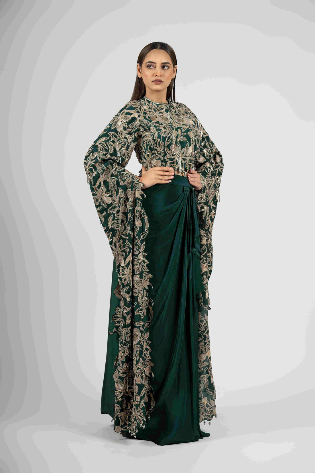 Green crepe crop top with cape sleeves and matching drape skirt embellished with kasab, sequins, thread, and cutdana embroidery – Indo-western festive outfit.