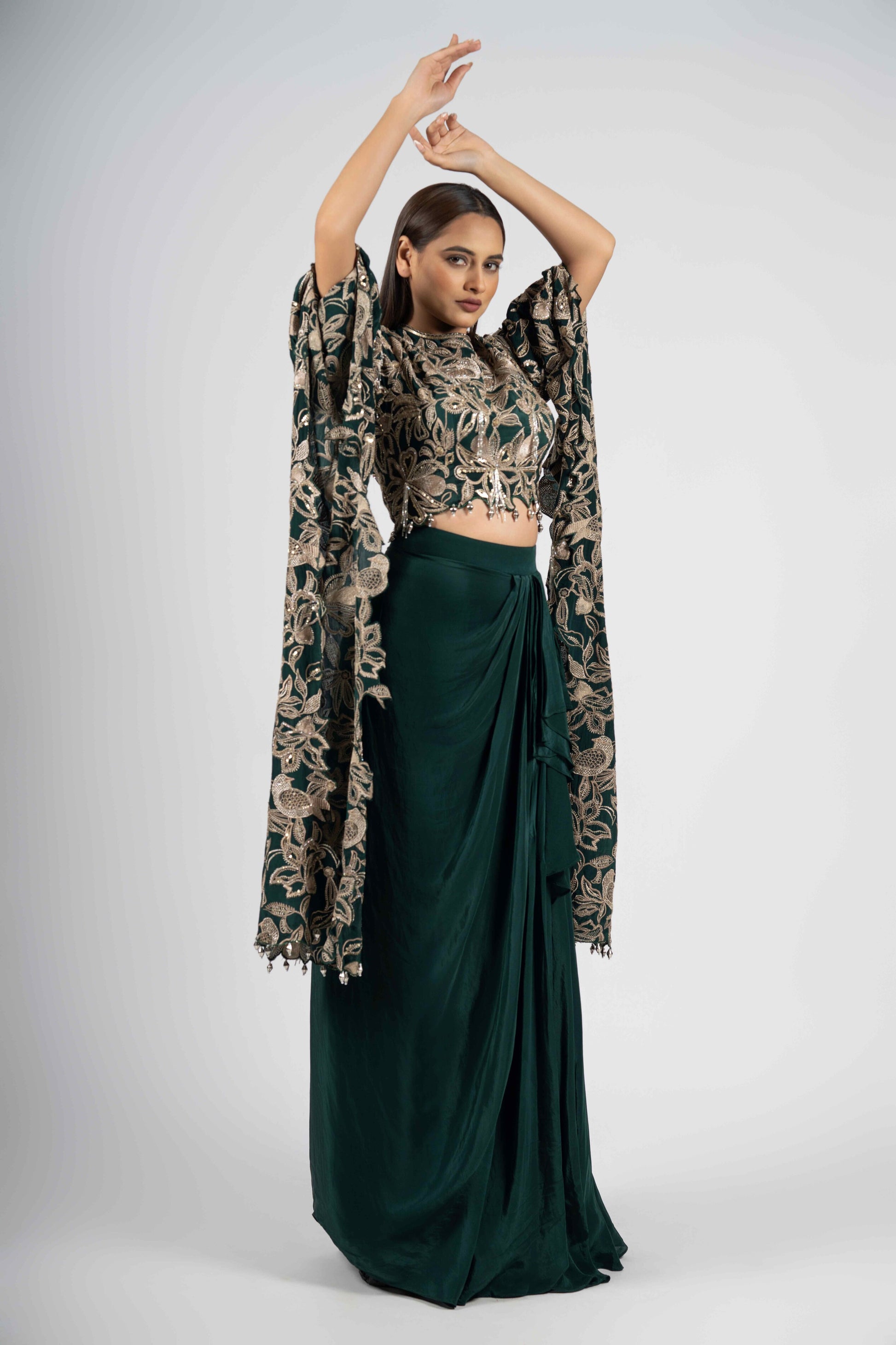 Green crepe crop top with cape sleeves and matching drape skirt embellished with kasab, sequins, thread, and cutdana embroidery – Indo-western festive outfit.