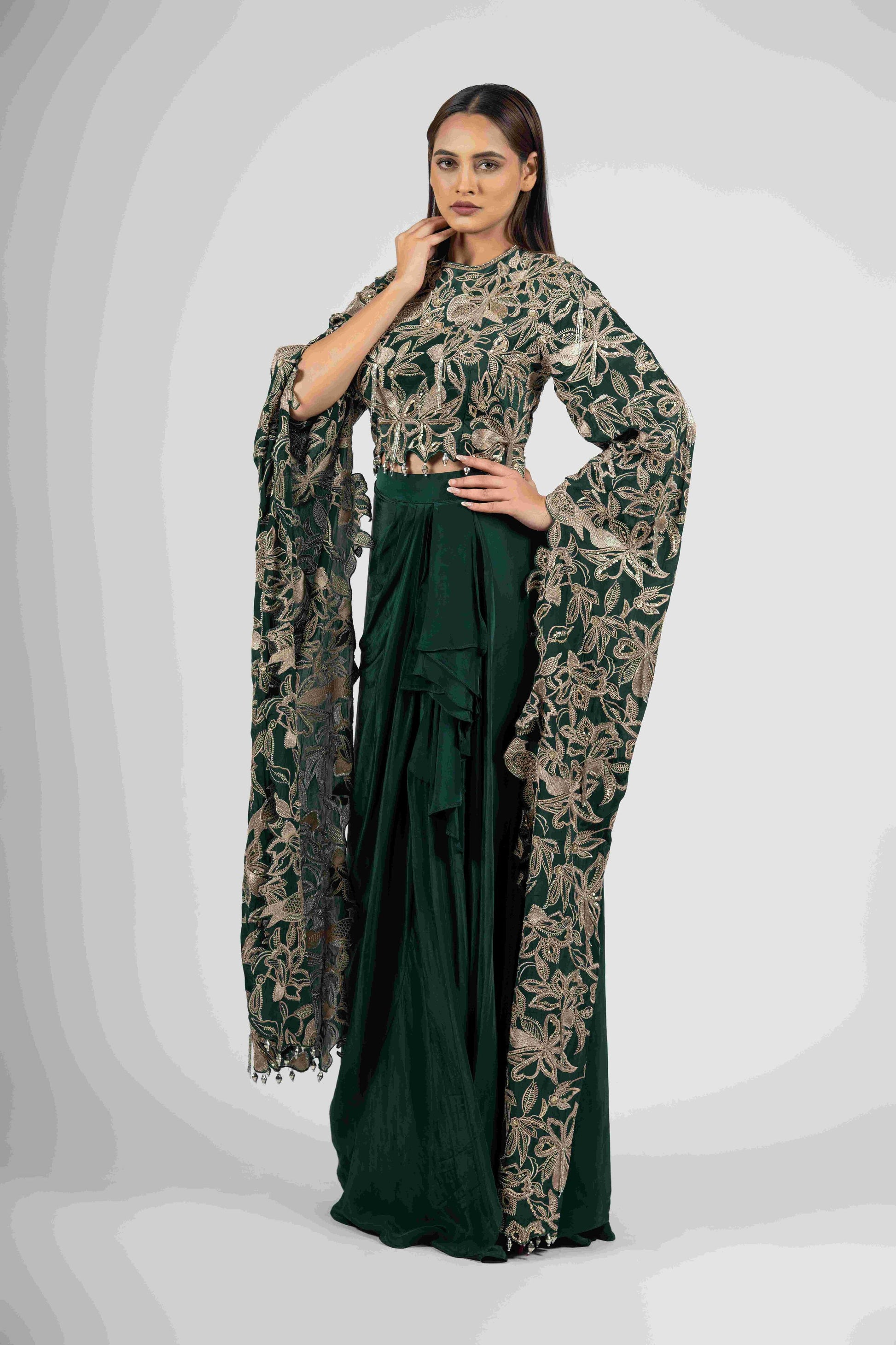 Green crepe crop top with cape sleeves and matching drape skirt embellished with kasab, sequins, thread, and cutdana embroidery – Indo-western festive outfit.