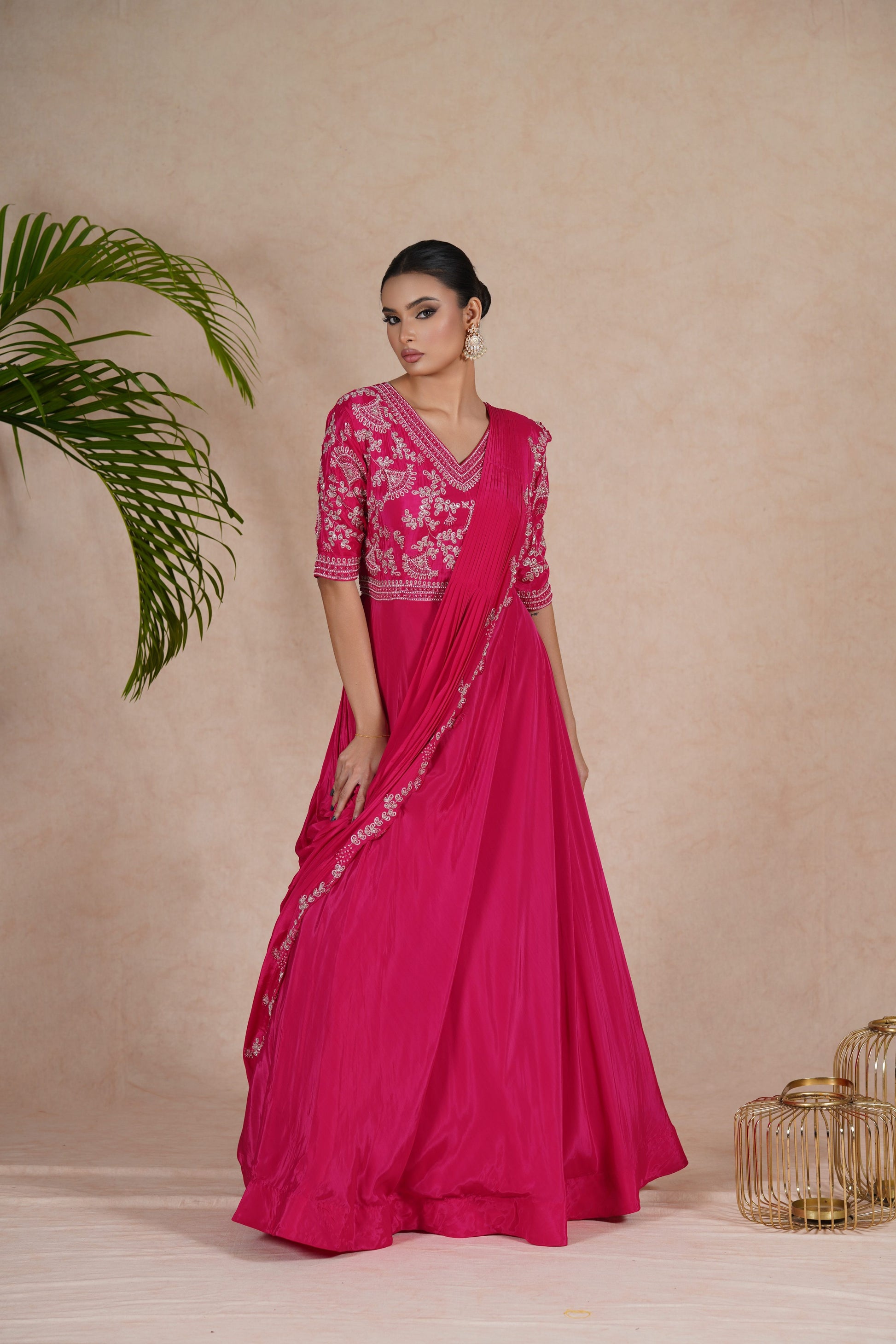 A hot pink embroidered gown with drape, featuring pearl, kasab, zardozi, sequins, and pitai work. Perfect for festive occasions and formal events.