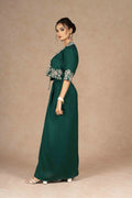 Model gracefully turning in a deep green Indo-Western Jacket Dress with a drape skirt, exuding sophistication and style.