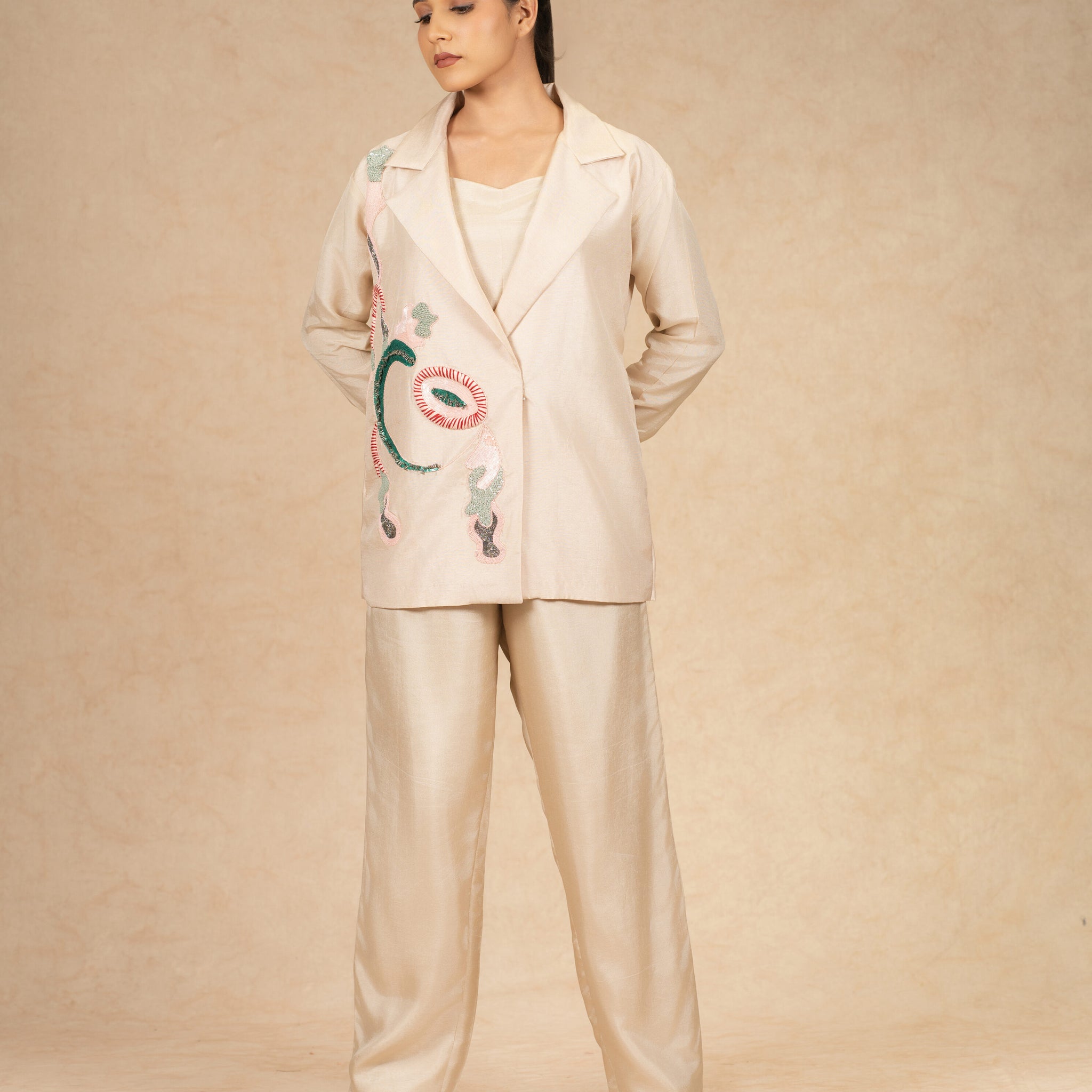 Model wearing an Ivory Silk Blazer with embroidered details, paired with wide-leg pants for a contemporary formal look.