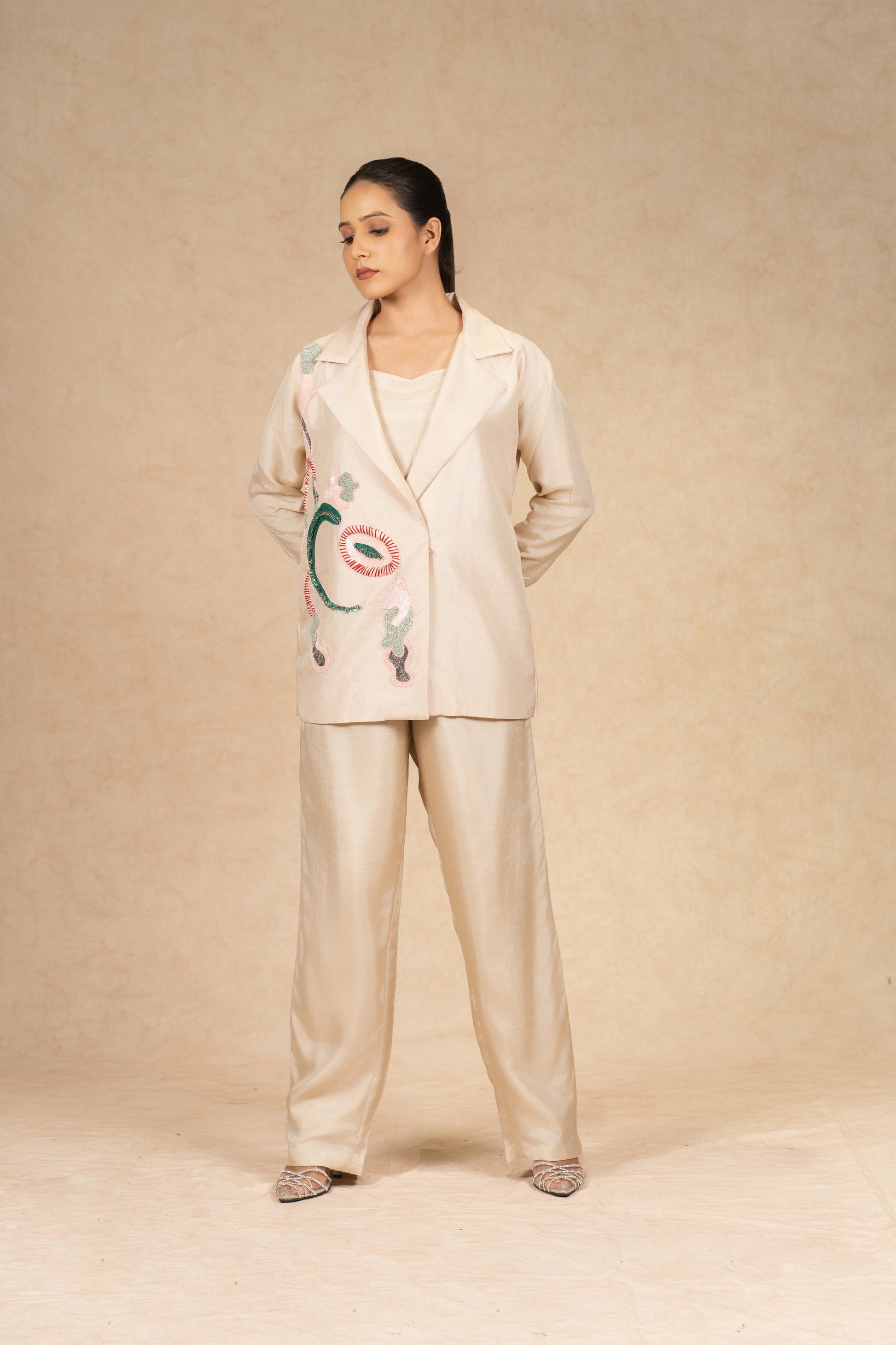 Model wearing an Ivory Silk Blazer with embroidered details, paired with wide-leg pants for a contemporary formal look.