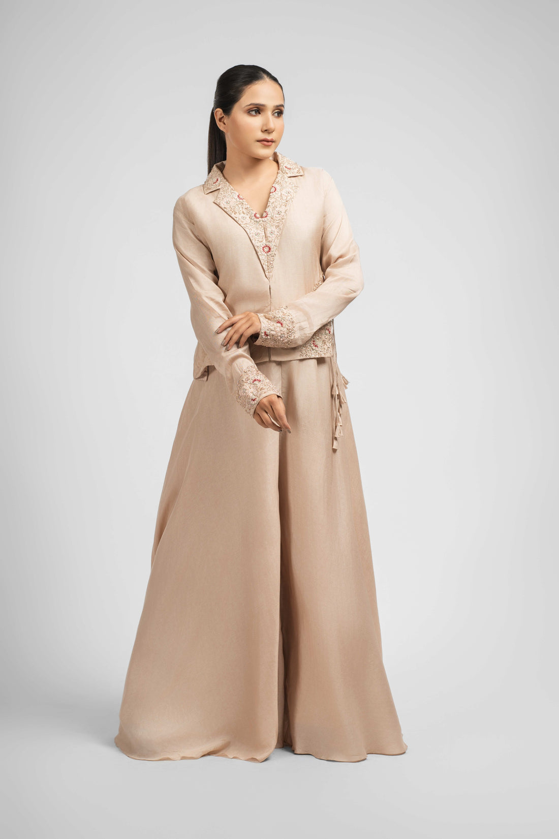 A stunning ivory silk Indowestern set featuring a lapped-collar embellished top with dori latkan details, paired with wide-leg umbrella palazzo pants, perfect for festive and formal occasions.