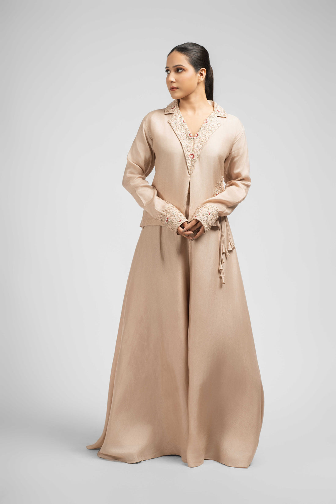 A stunning ivory silk Indowestern set featuring a lapped-collar embellished top with dori latkan details, paired with wide-leg umbrella palazzo pants, perfect for festive and formal occasions.