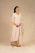 Light peach Chanderi suit with pants and an organza dupatta featuring floral embroidery, pearl embellishments, and pleated detailing, perfect for festive and formal occasions.