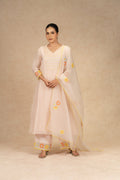 Light peach Chanderi suit with pants and an organza dupatta featuring floral embroidery, pearl embellishments, and pleated detailing, perfect for festive and formal occasions.