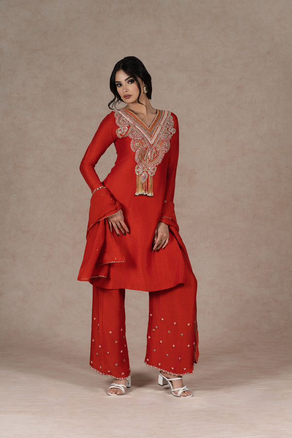 Orange silk kurta set with gold hand embroidery on the neckline, sleeves, and dupatta, paired with embroidered pants. Elegant festive wear with a modern touch.