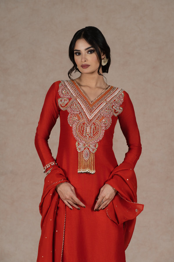 Orange silk kurta set with gold hand embroidery on the neckline, sleeves, and dupatta, paired with embroidered pants. Elegant festive wear with a modern touch.