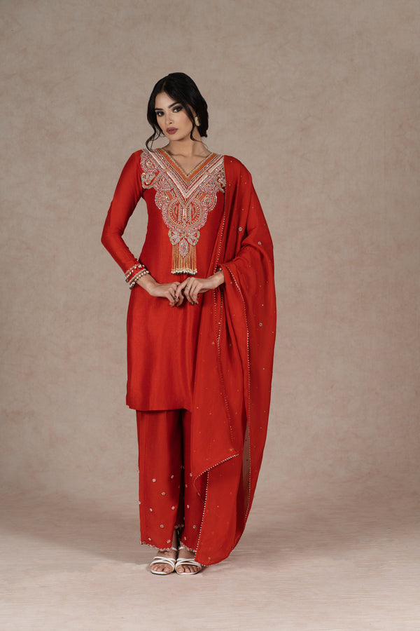 Orange silk kurta set with gold hand embroidery on the neckline, sleeves, and dupatta, paired with embroidered pants. Elegant festive wear with a modern touch.