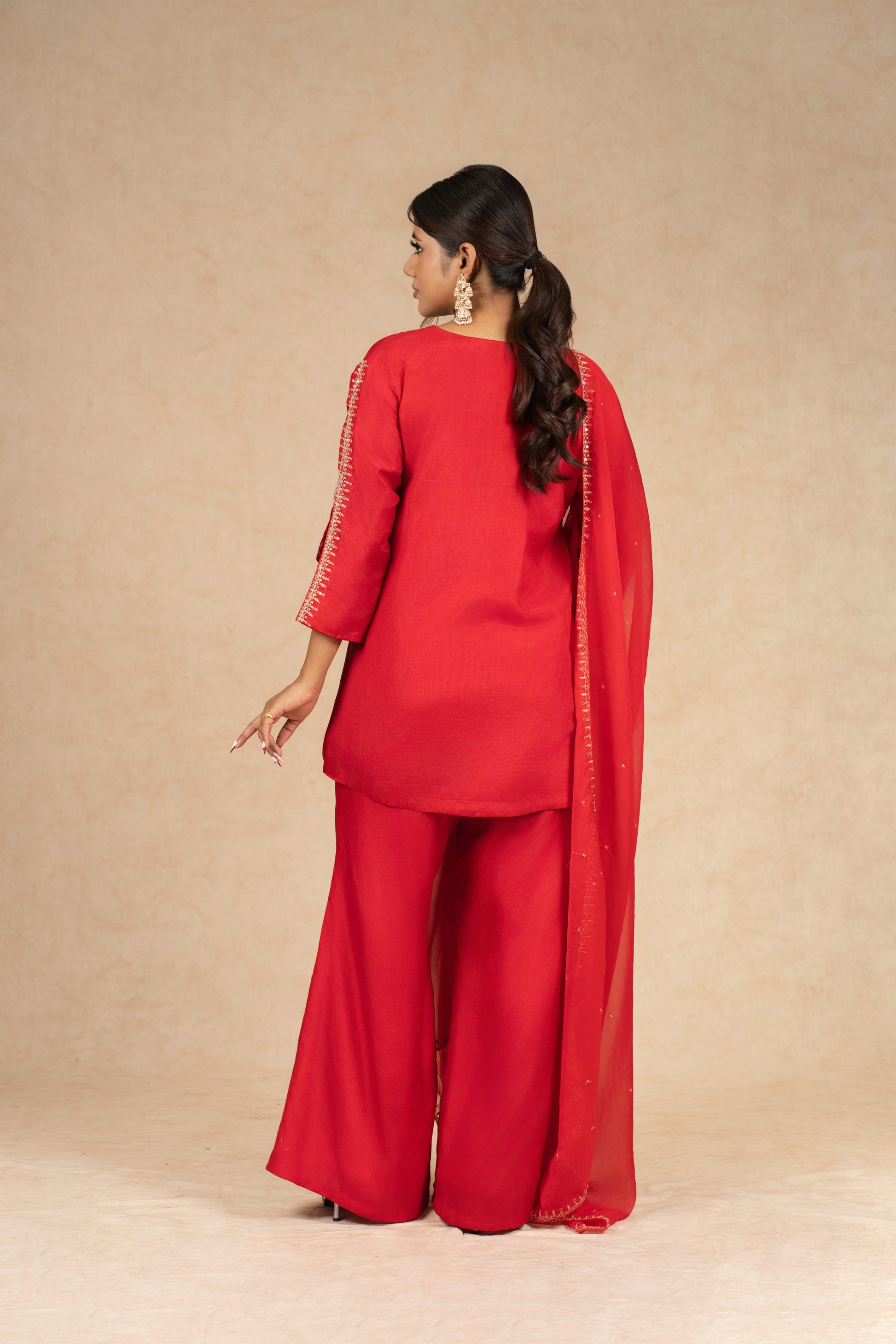 Artistic pose emphasizing the intricate craftsmanship and luxurious appeal of the Red Silk Suit.