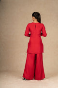 Back view of a red silk suit, showcasing the elegant silhouette and minimalist back design with a keyhole detail.