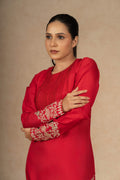 Close-up of a model in a red silk suit, emphasizing the fine embroidery on the sleeves and the luxurious texture of the fabric.