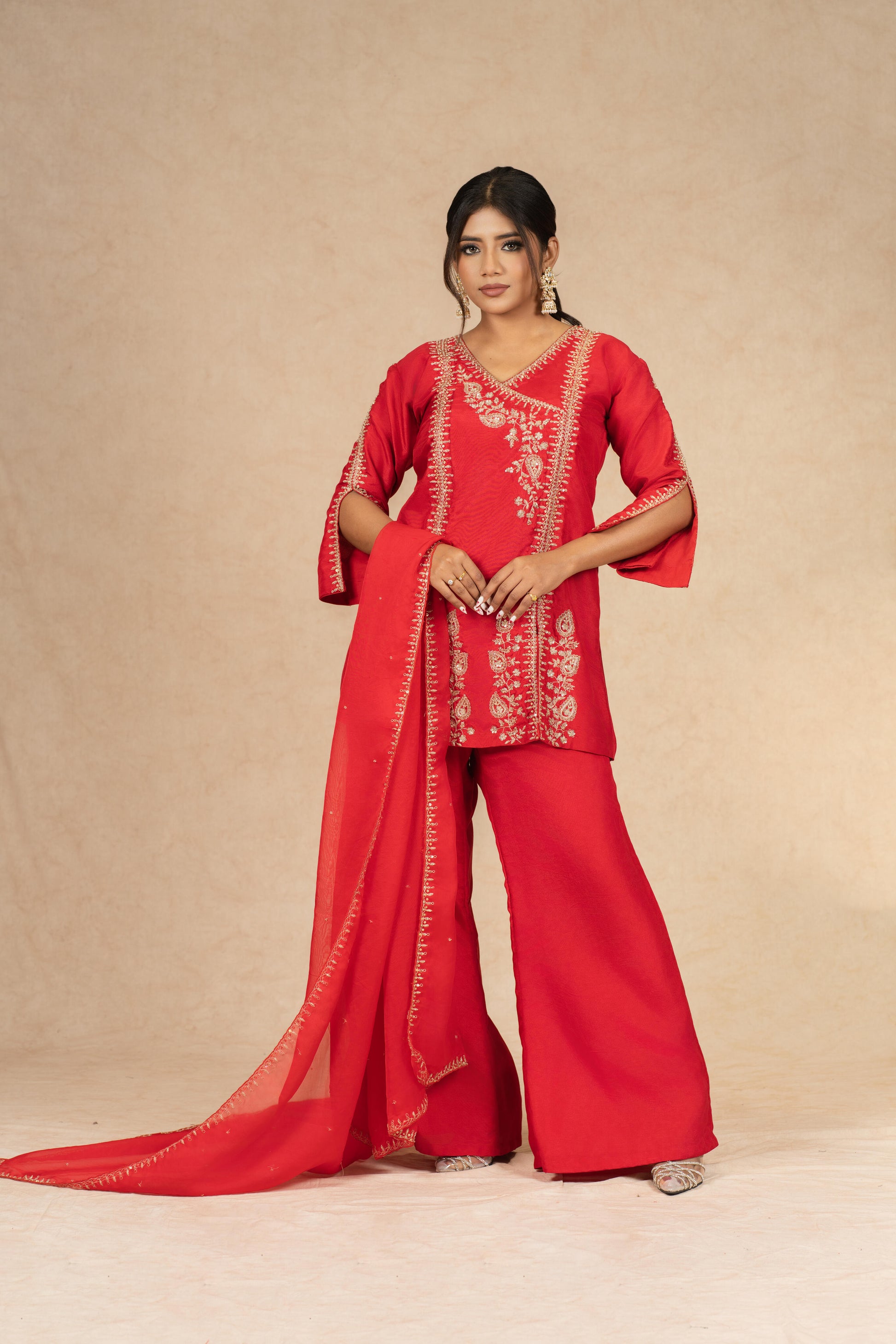 Dramatic pose highlighting the beauty of the Red Silk Suit with its exquisite dabka and pearl work.