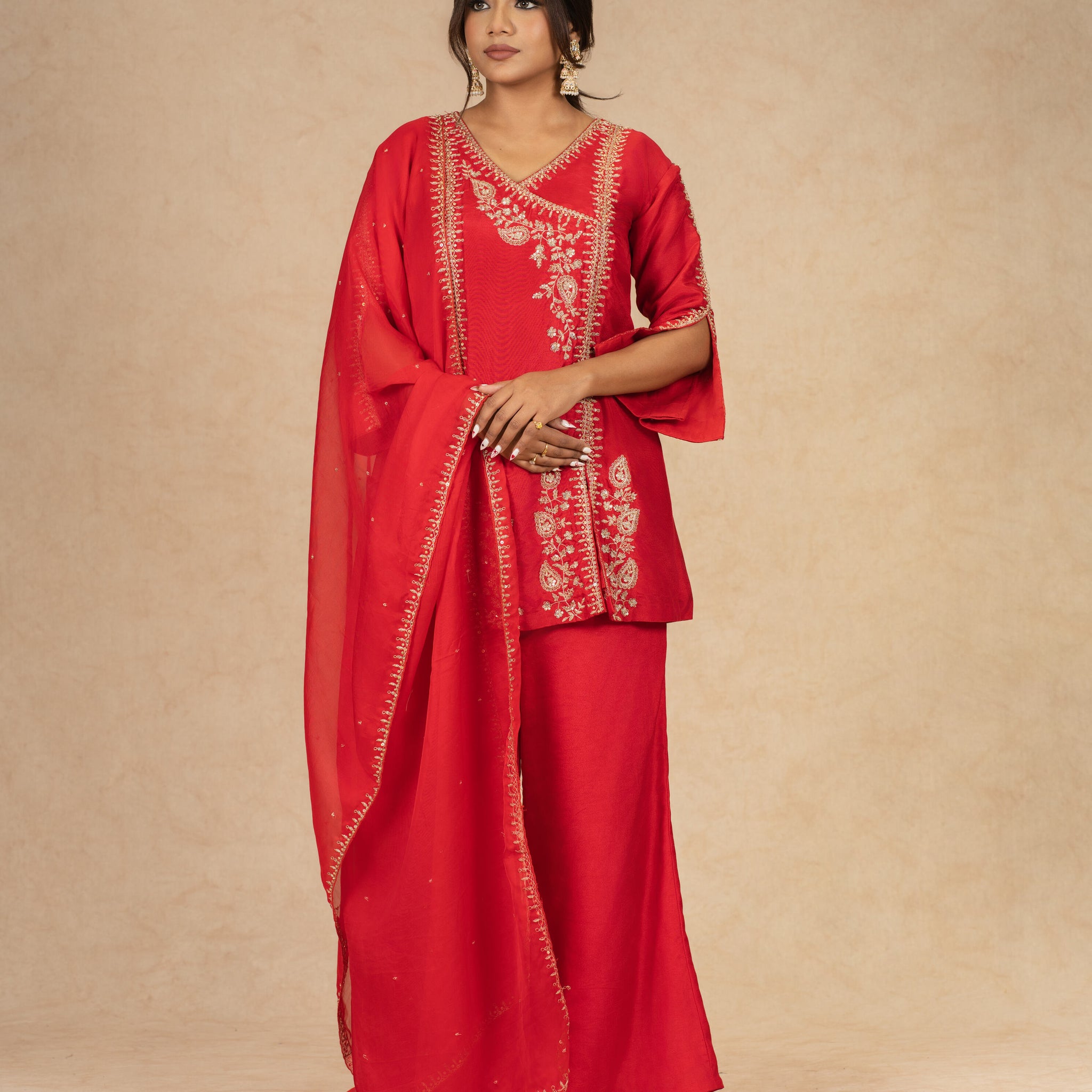 Elegant pose in Red Silk Suit featuring flared pants and an organza dupatta with dabka, sequins, and pearl embellishments.
