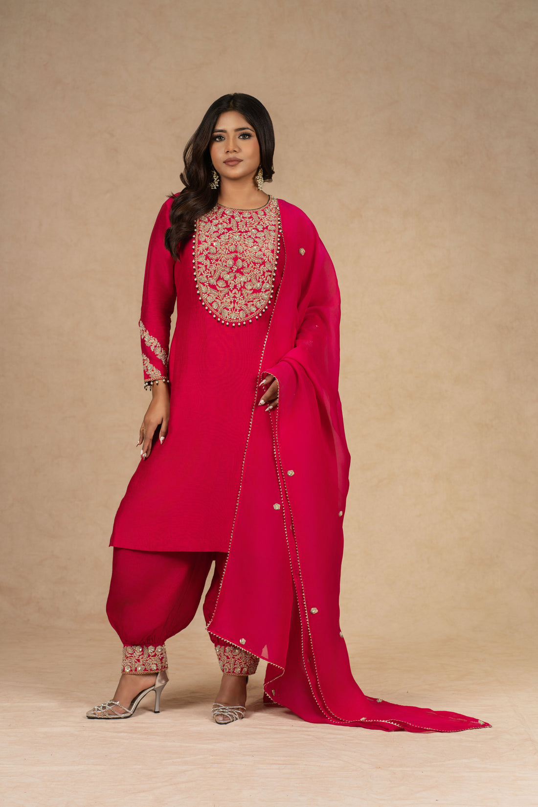 Model posing gracefully in a Red Straight Silk Suit with a fully embroidered neckline and matching dupatta, paired with detailed pants.