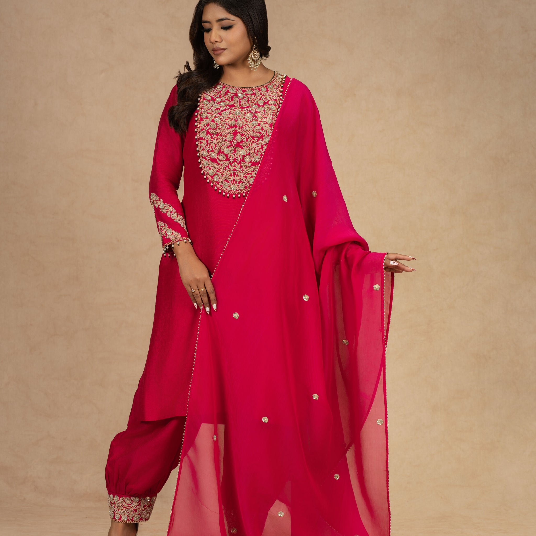 Model posing gracefully in a Red Straight Silk Suit with a fully embroidered neckline and matching dupatta, paired with detailed pants.