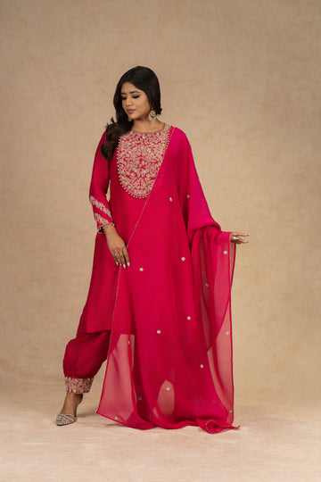 Model posing gracefully in a Red Straight Silk Suit with a fully embroidered neckline and matching dupatta, paired with detailed pants.