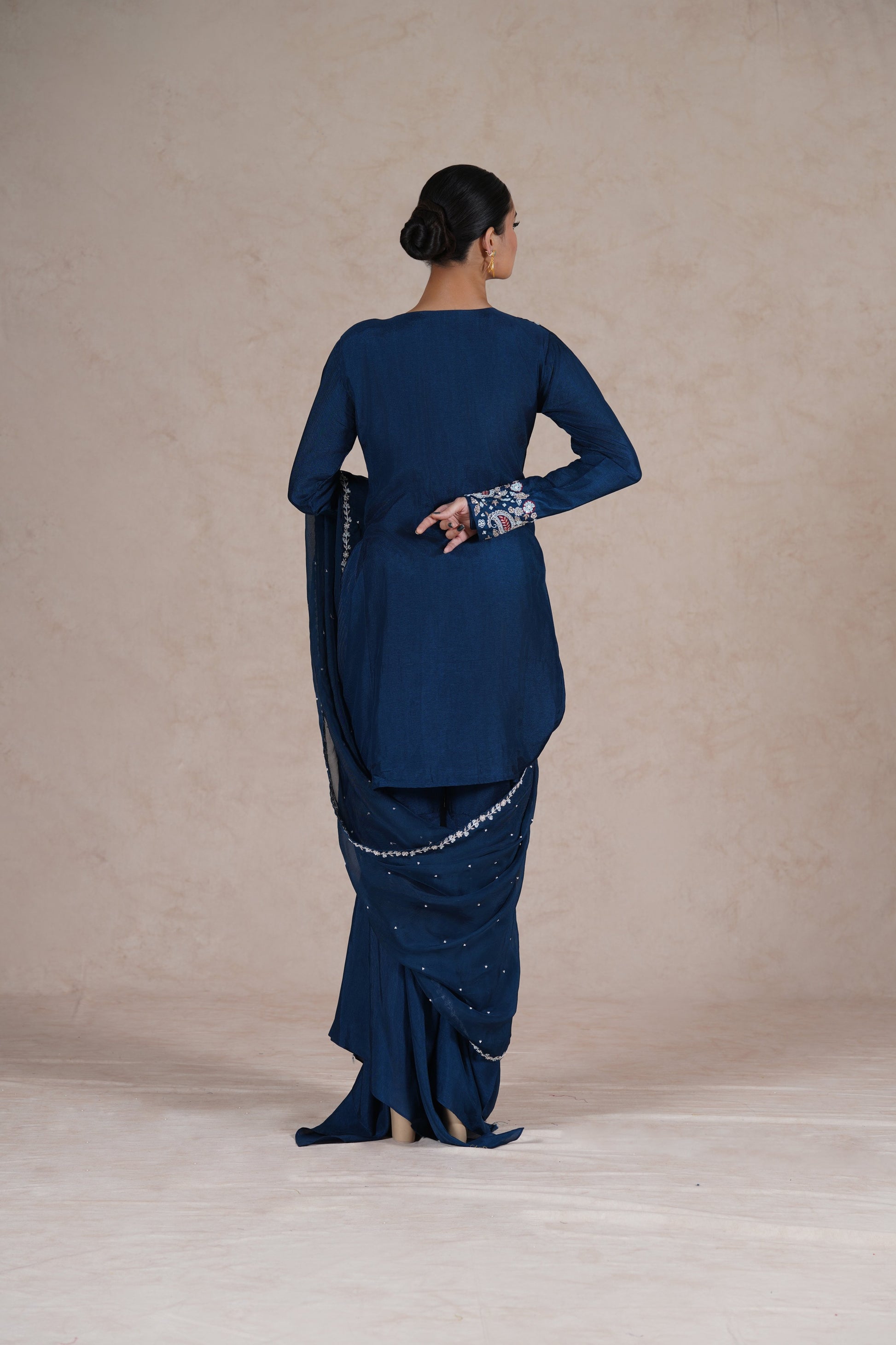 A back view of a model wearing a royal blue embroidered suit, showcasing the elegant drape of the dupatta.