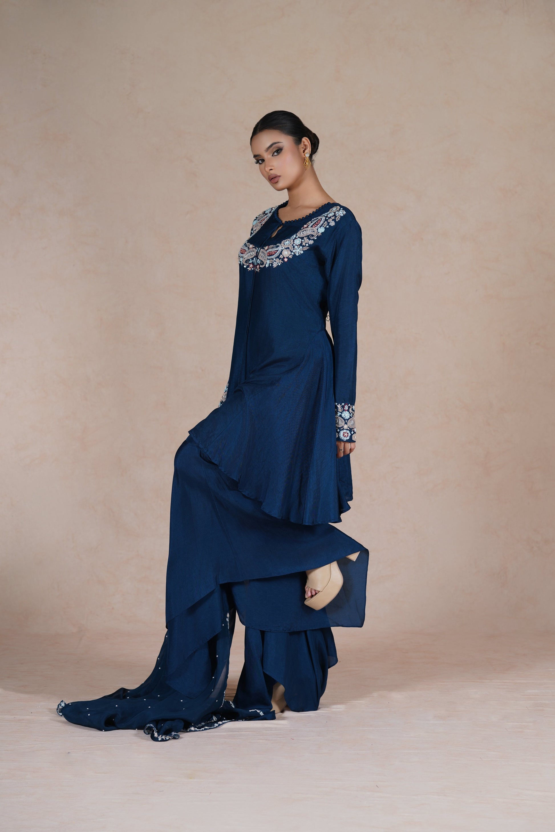 A model striking a stylish pose in a royal blue embroidered suit, featuring intricate embroidery on the neckline and sleeves.