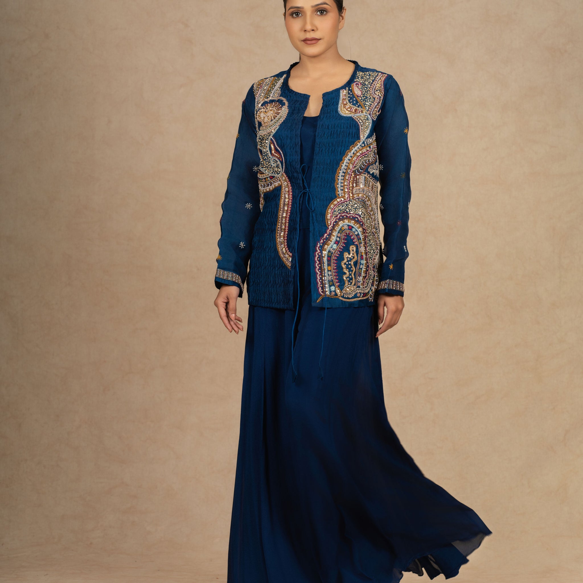 Royal blue Indo Western outfit with intricate embroidery on an organza jacket, paired with a flowy skirt.
