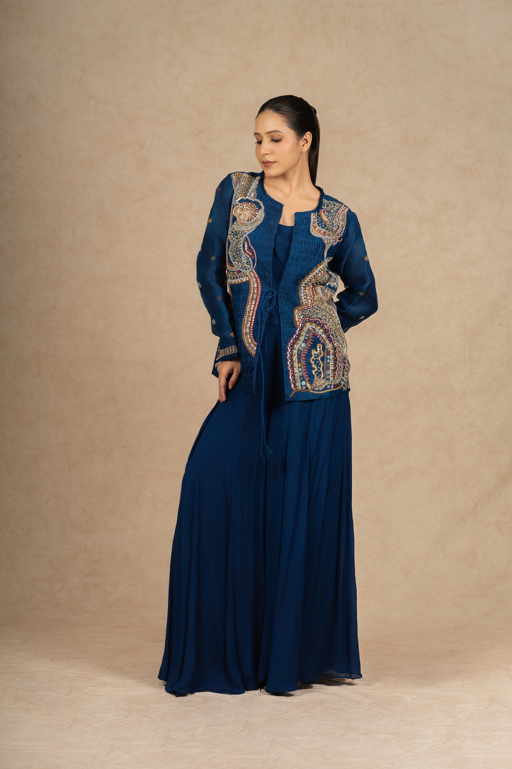 Side pose of the royal blue Indo Western outfit, showcasing intricate embellishments and fluid draping.
